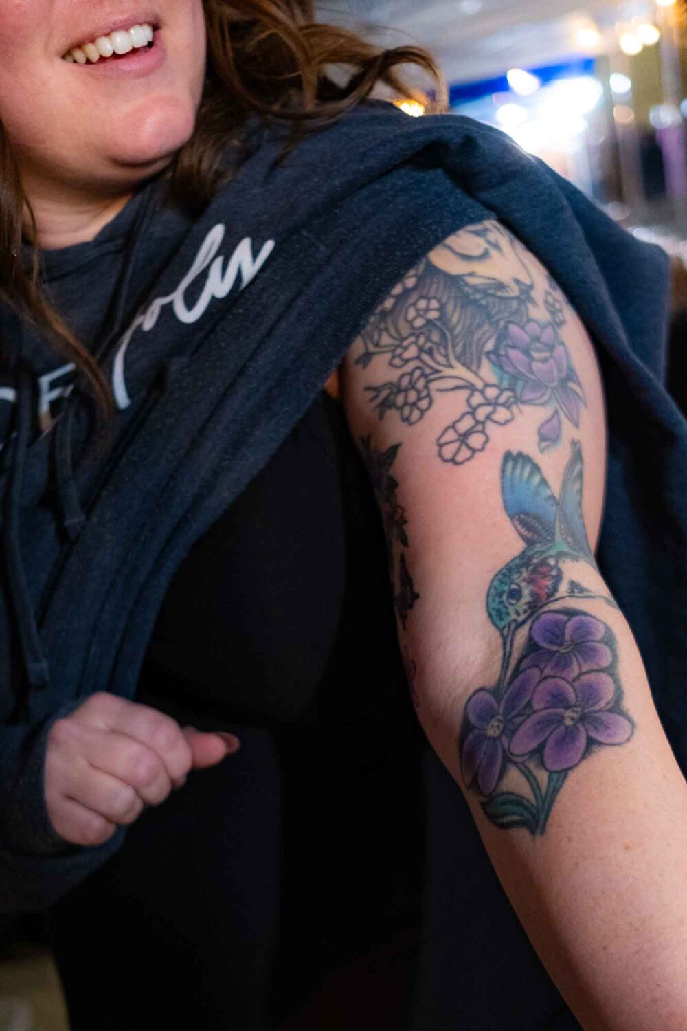 Breanna Jackson lifts her sleeve to show the hummingbird tattoo on her arm