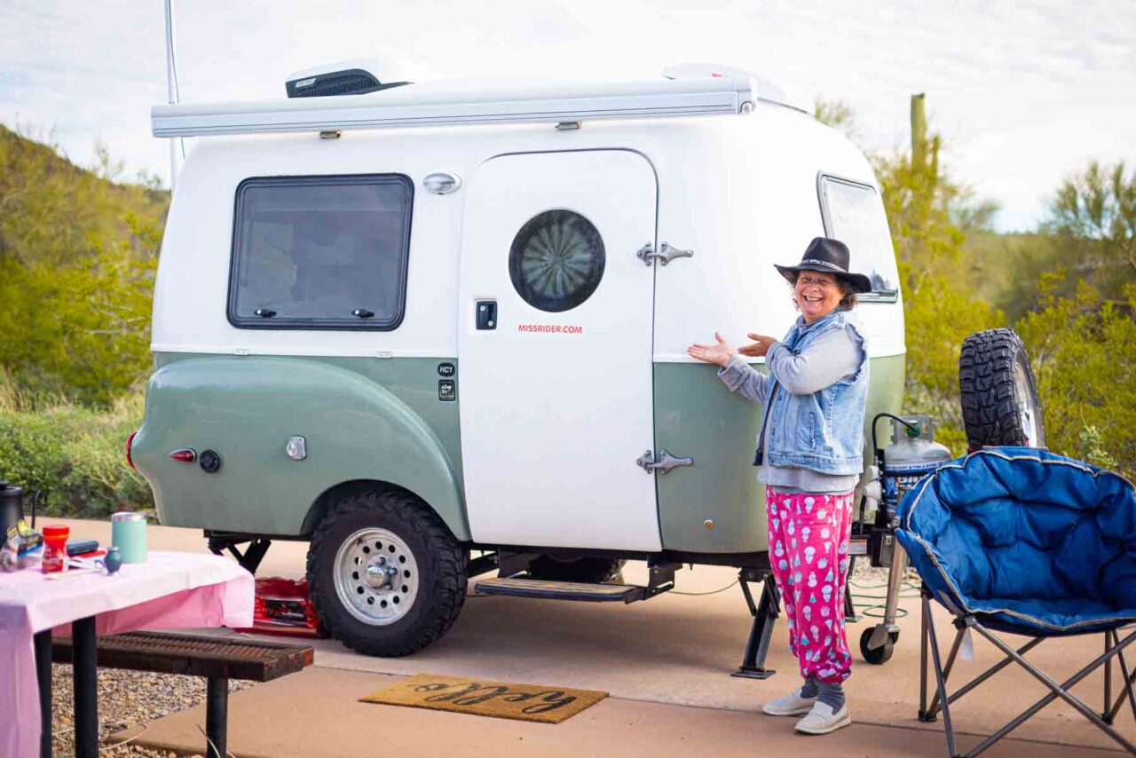 Miss rider laughs as she sits in front of her tiny camper